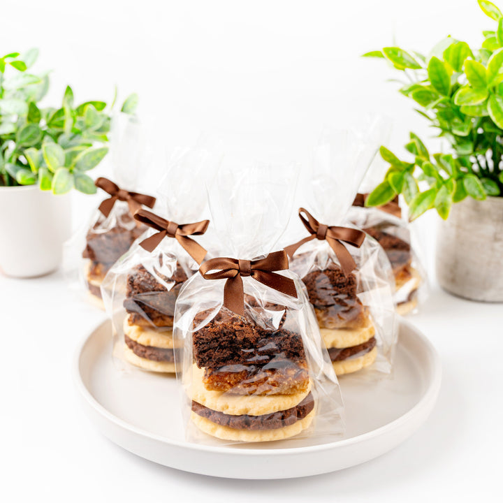 Baked goods in clear packaging on a white plate with green plants in the background