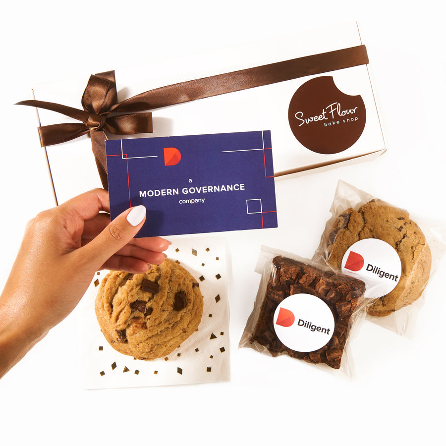 Cookies with branded stickers and a gift card held by a hand on a white background