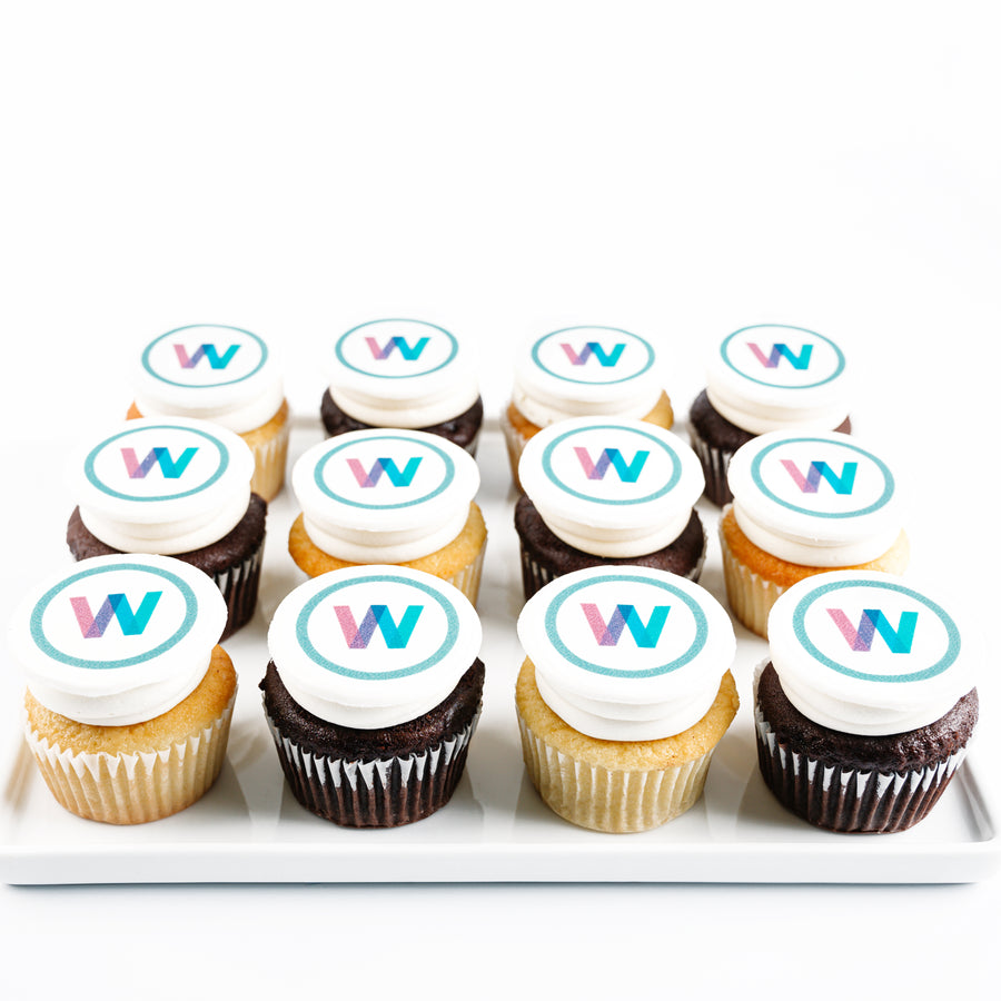 Assorted cupcakes with white frosting and 'W' logo on a white tray