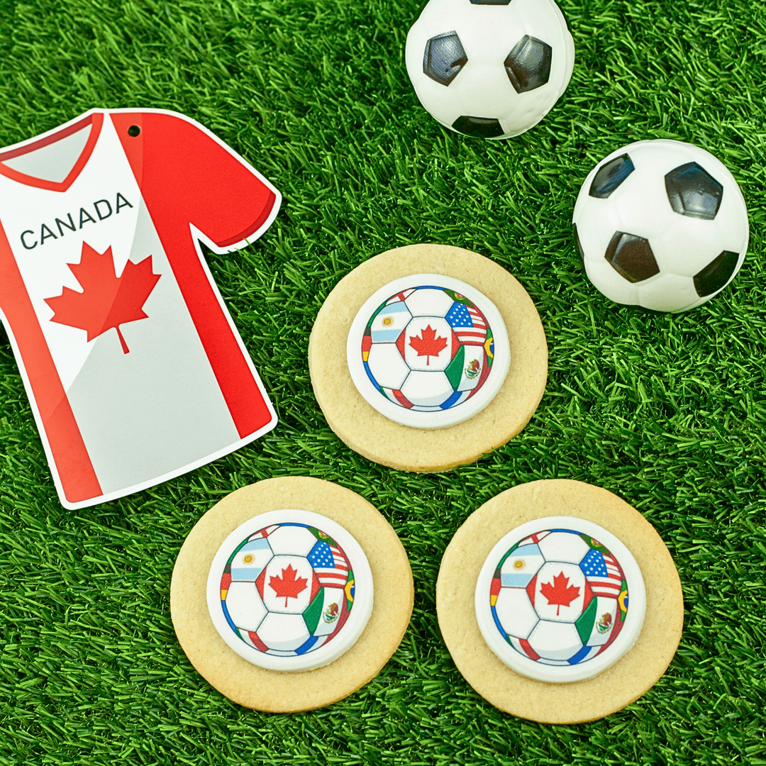 Cookies with soccer ball designs on a grassy background, featuring a Canada-themed shirt.