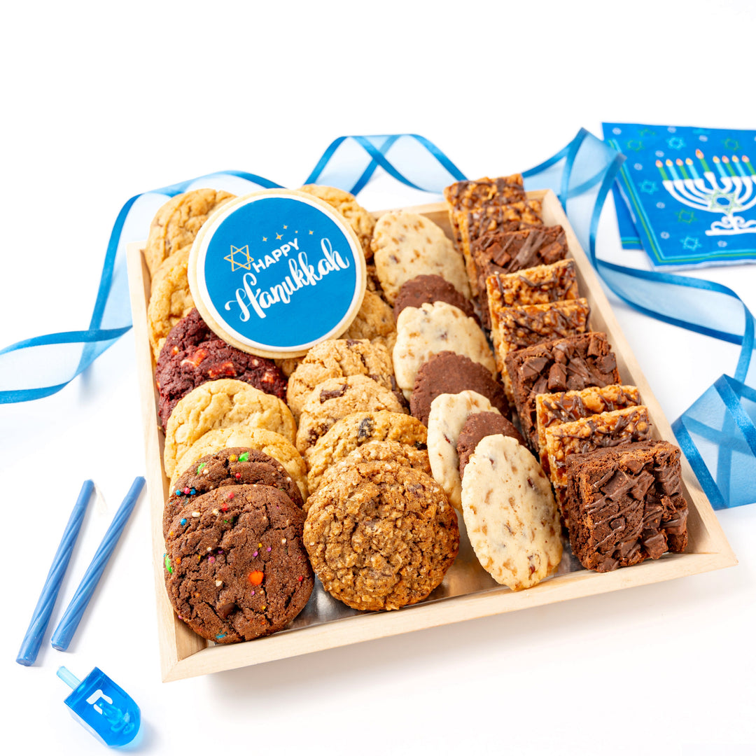Assorted cookies in a wooden gift tray with Hanukkah-themed decorations on a white background