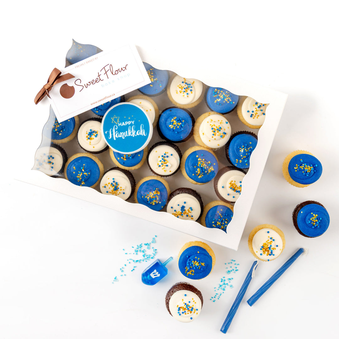 Packaged Hanukkah cupcakes with blue and yellow icing on a white background