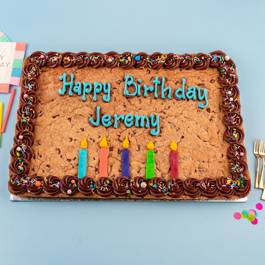 Cookie birthday cake with candles and 'Happy Birthday Jeremy' text on a blue background