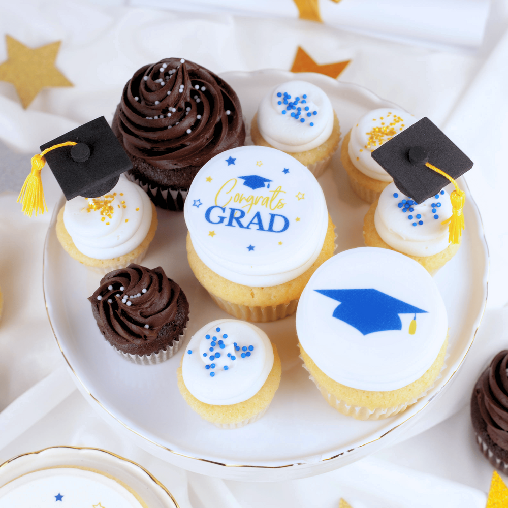Graduation-themed cupcakes with caps on a white plate.