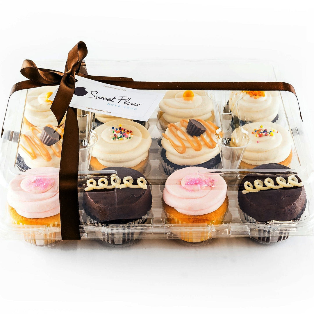 one dozen assorted cupcakes in clamshell with brown ribbon