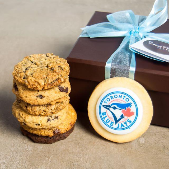 6 cookies stacked in front of Toronto Blue Jays logo cookie and brown Sweet Flour gift box with blue ribbon